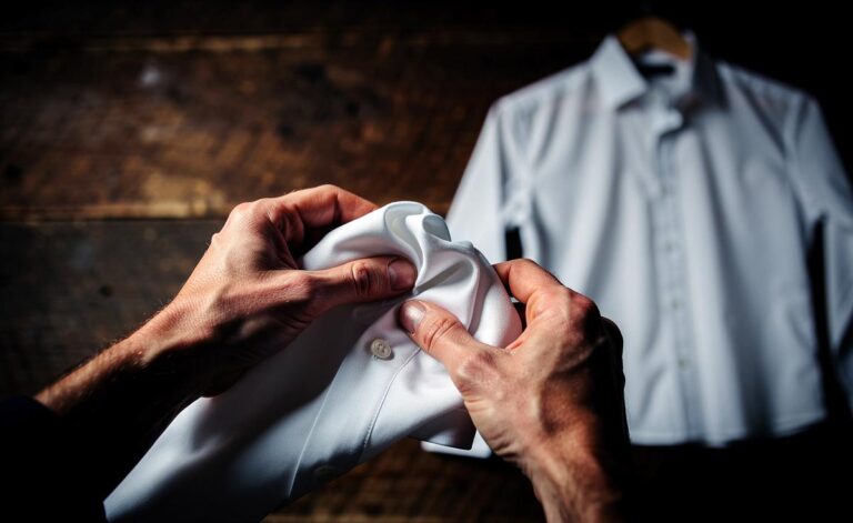 Illustration von zwei Händen, die ein weißes Hemd vor einem Bügelbrett locker in den Fäusten zerknittern, während daneben ein perfekt gebügeltes Hemd auf einem Kleiderbügel hängt.